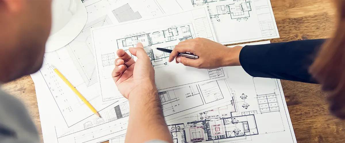 Architects reviewing detailed construction blueprints and floor plans for residential or commercial building design.