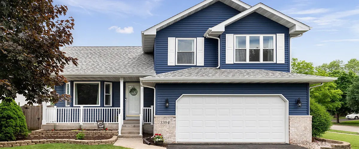 Modern blue suburban home with white trim and a well-maintained lawn.