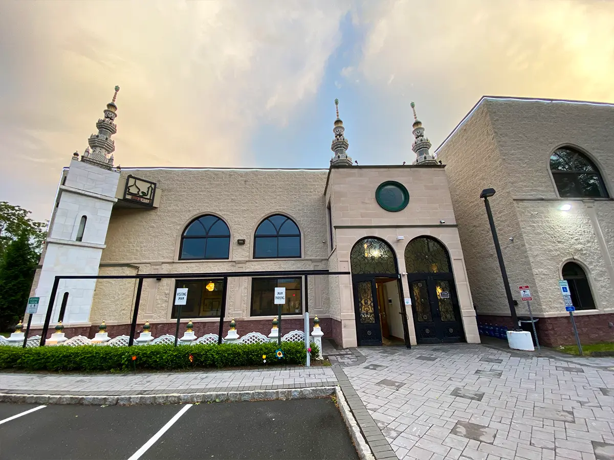 Al-Wali Center mosque facade at sunset, featuring intricately designed entryways and a landscaped pathway.