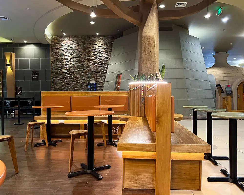 Juice bar seating area with wooden benches, tables, and soft lighting, creating a welcoming environment for customers.