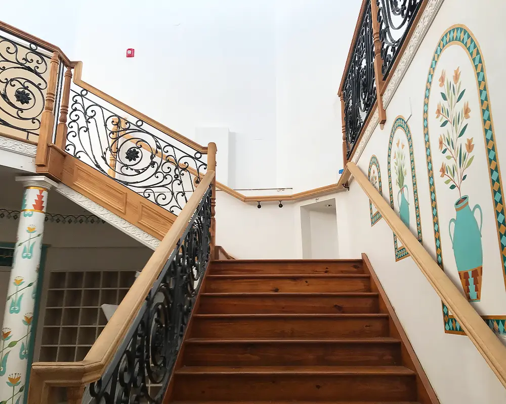 Ornate staircase with wrought iron railings and wooden steps in a beautifully designed interior space.