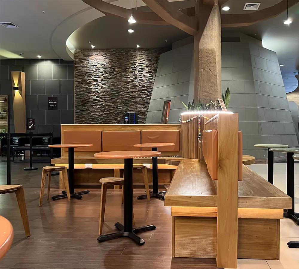 Modern restaurant seating area with wooden furniture and a stone accent wall for cozy dining ambiance.