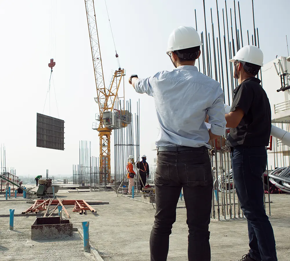 Construction site with workers, crane, and steel structures, showcasing active project management and teamwork.