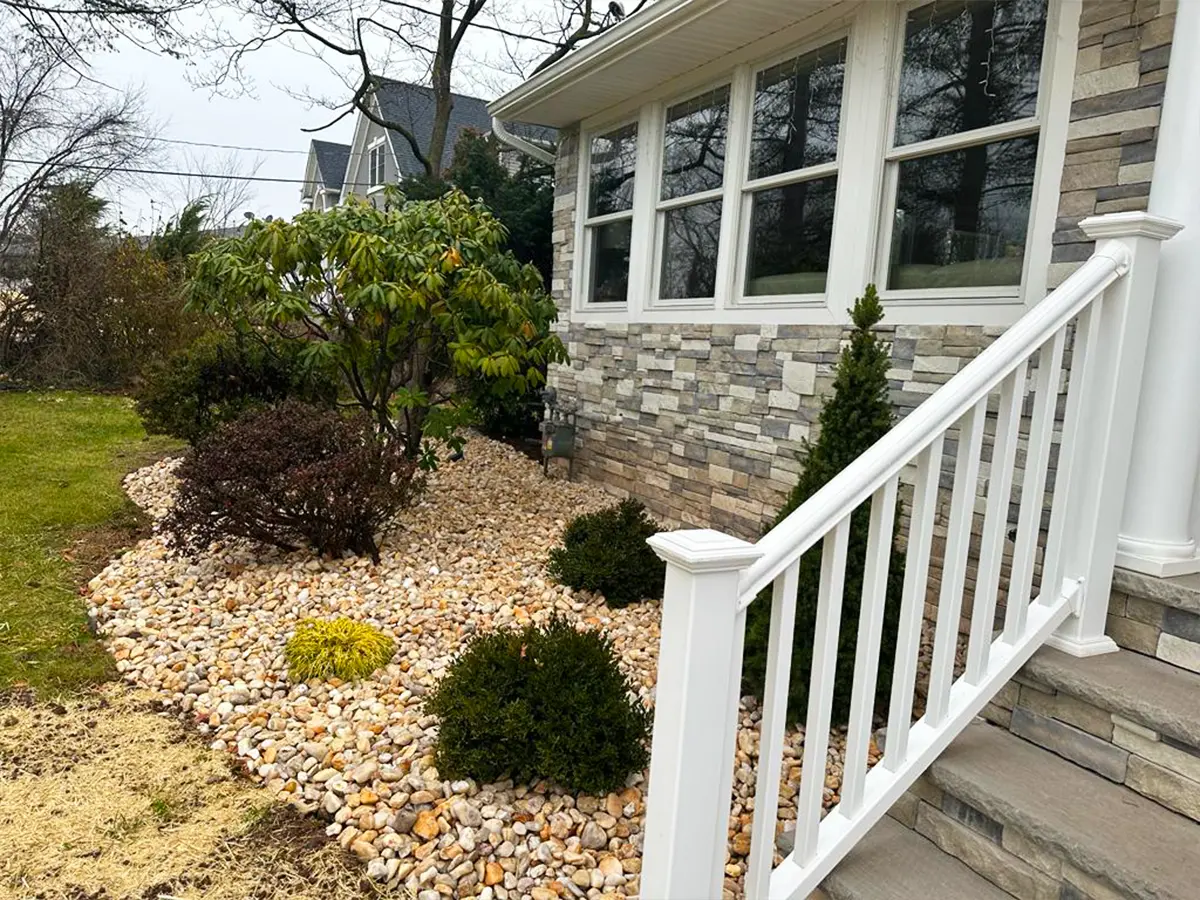 Landscaped garden with pebble pathway and white railings at the front porch.