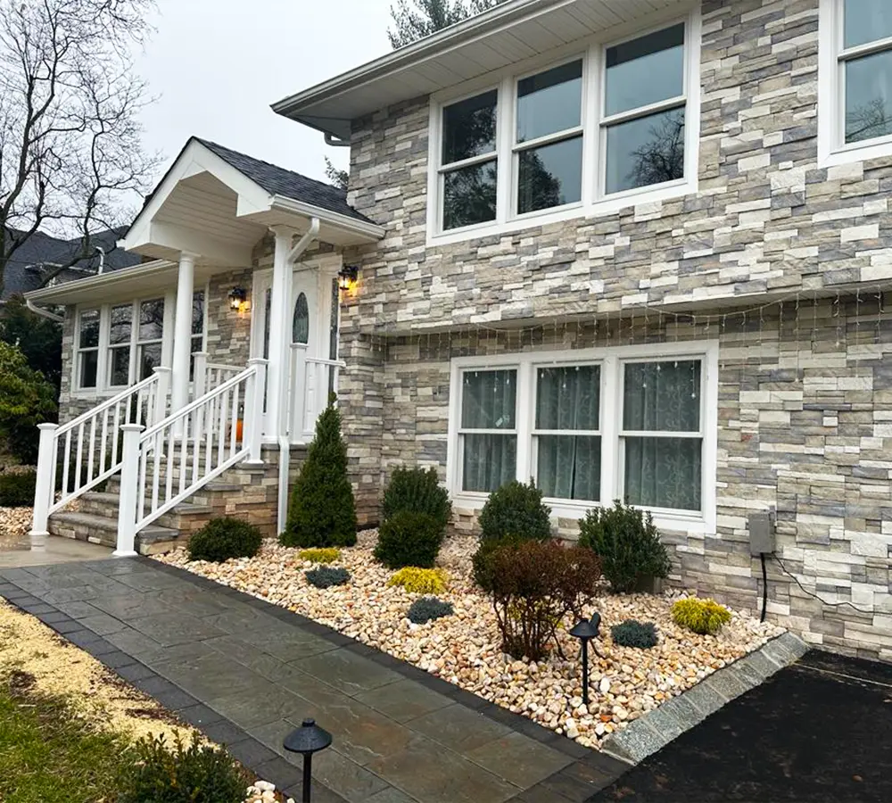 Close-up of stone-clad house facade with detailed landscaping.