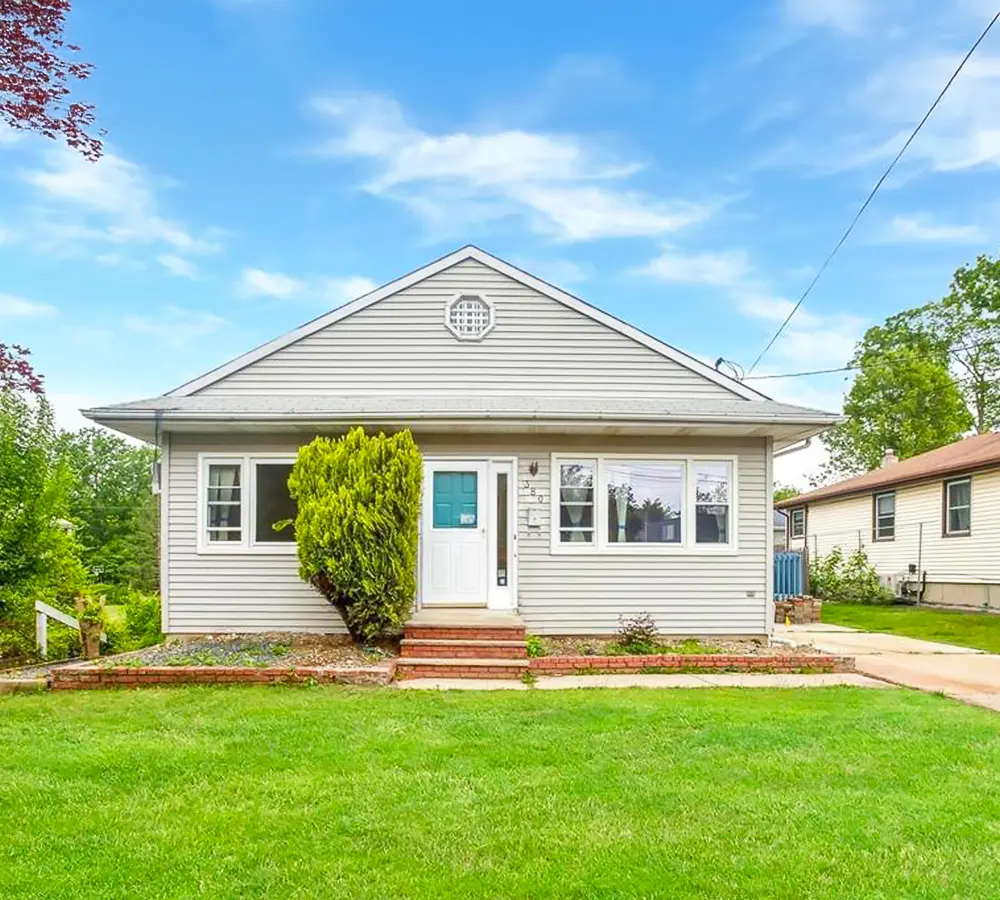 Beautifully renovated home exterior with white siding, vibrant greenery, and a welcoming entrance for remodeling showcase.