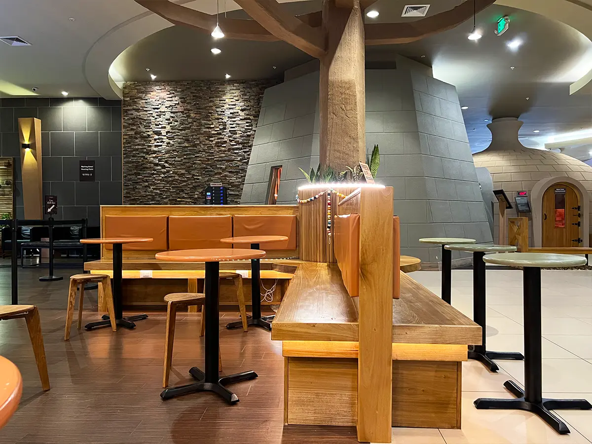 Juice bar seating area with wooden benches, tables, and soft lighting, creating a welcoming environment for customers.