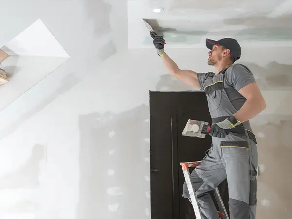 Professional construction worker repairing a ceiling during a home renovation project, showcasing skilled craftsmanship.