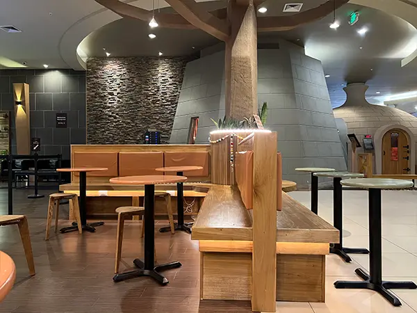 Modern restaurant interior with wood tables, booth seating, and contemporary stone wall accents.