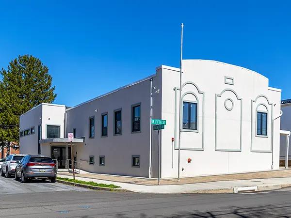 Exterior of a white, single-story community center on a sunny day