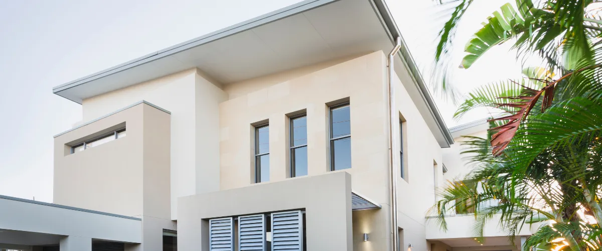 Elegant modern luxury home with a white facade, large windows, and tropical landscaping.