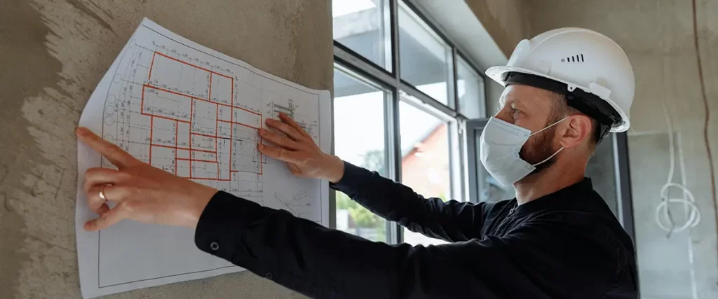 Construction worker reviewing building plans on site