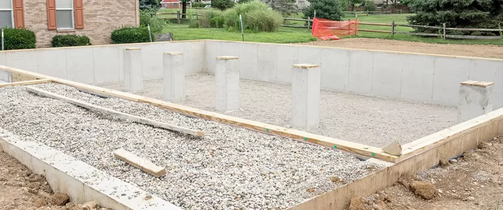 Concrete crawl space foundation perimeter walls with central concrete piers (posts), built on a gravel base to provide stability against clay soil in Middlesex County.