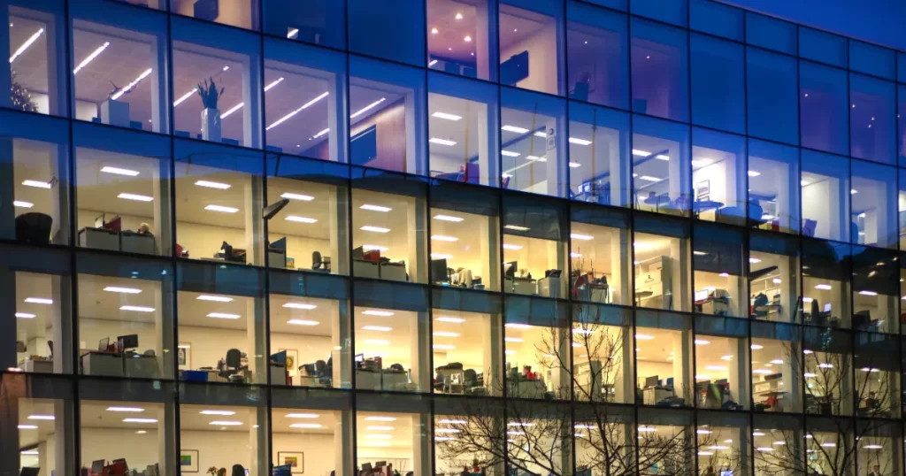 an office building at dusk or night, with many of the interior lights on in the individual office spaces