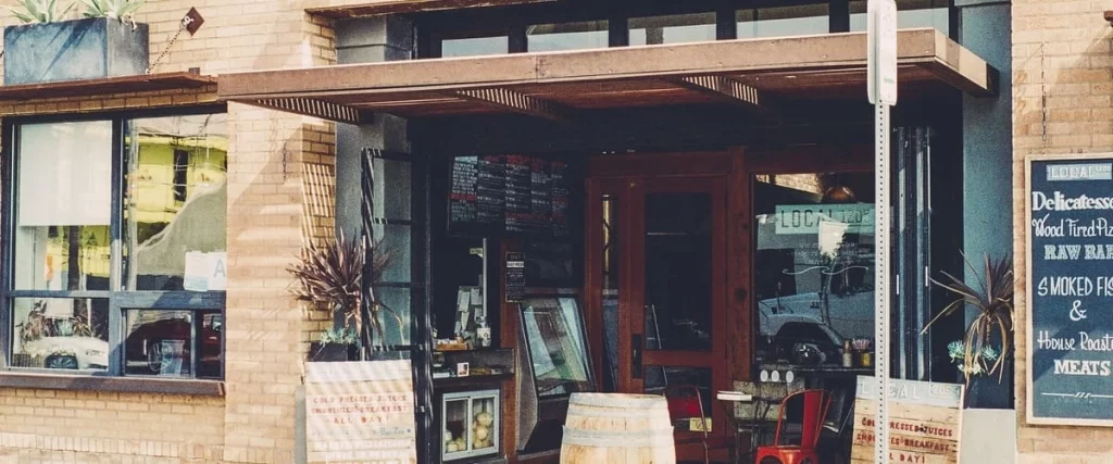 Brick deli exterior featuring chalkboard menus, glass windows, and a wooden overhang.