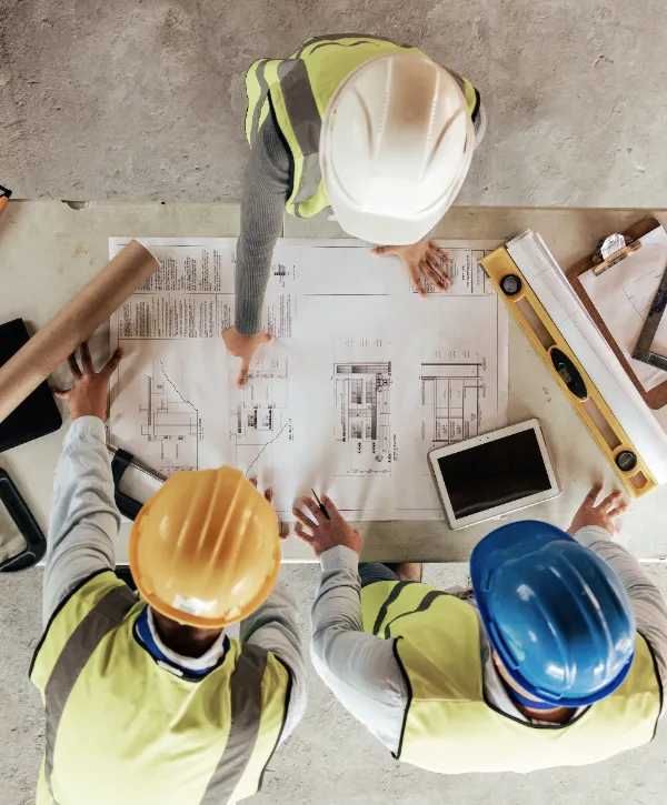 three construction professionals reviewing an engineering drawing or blueprint